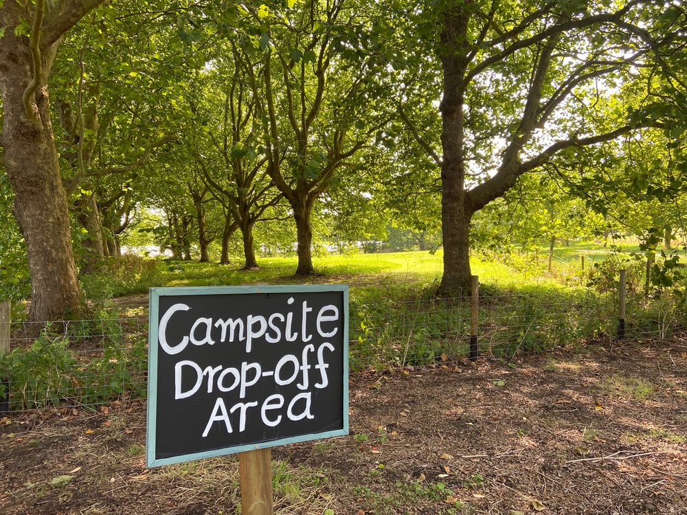 An entrance to a self-pitch camping meadow, displaying a camspite drop off signage