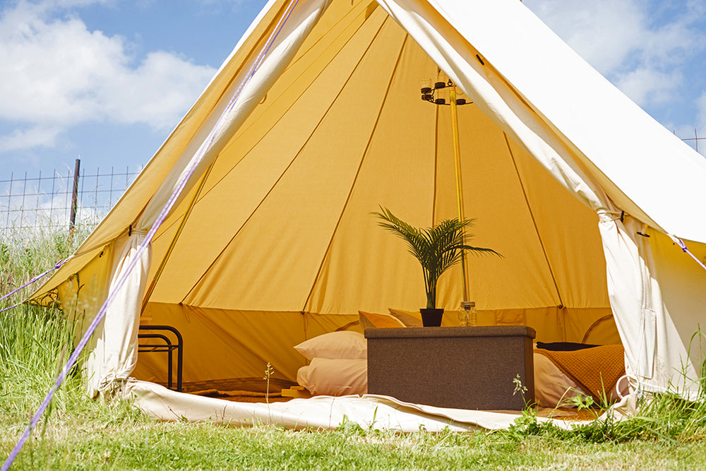 A bell tent with it's front curtains open to reveal the furnished interior